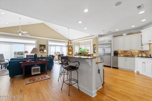 kitchen featuring white cabinets, open floor plan, stainless steel appliances, and a breakfast bar area