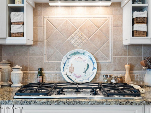 room details featuring stainless steel gas stovetop, decorative backsplash, and white cabinetry