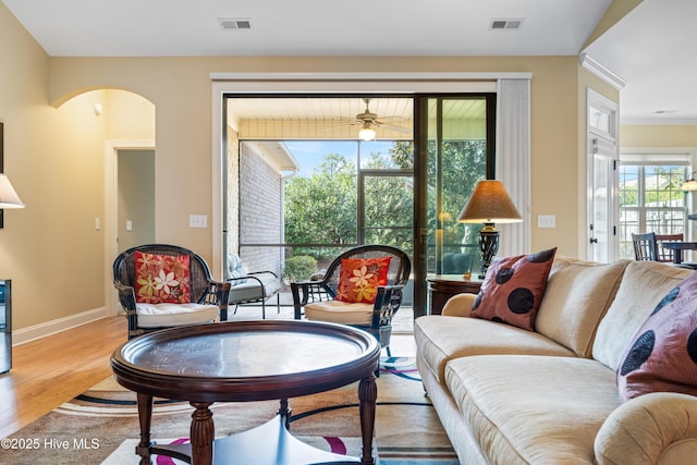 living area featuring baseboards, visible vents, arched walkways, and wood finished floors