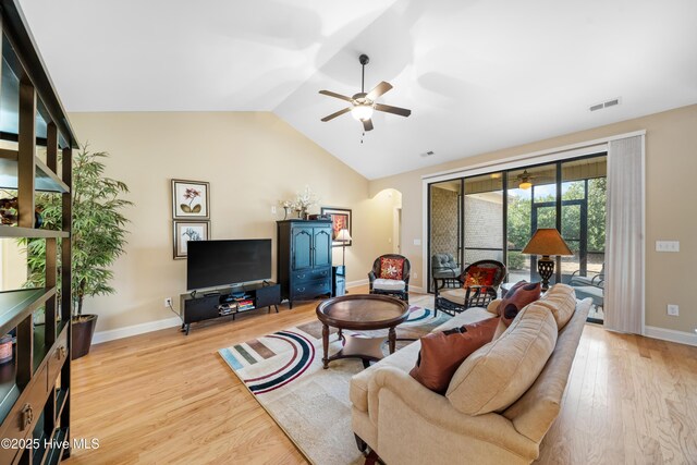 living room featuring arched walkways, ceiling fan, wood finished floors, visible vents, and vaulted ceiling