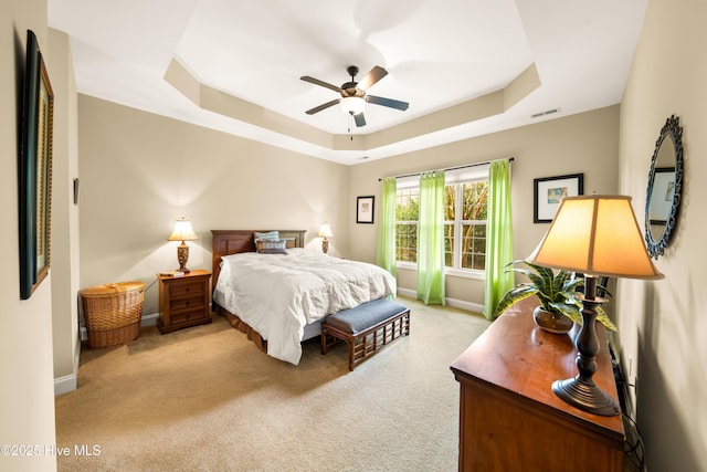 bedroom with light carpet, baseboards, visible vents, and a raised ceiling