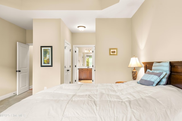 carpeted bedroom featuring baseboards and connected bathroom