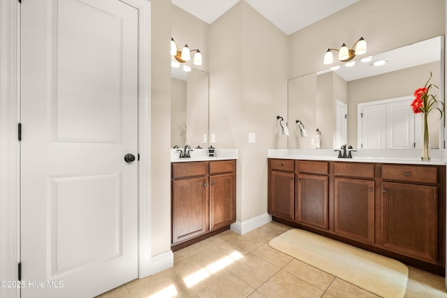 bathroom with a sink, baseboards, two vanities, and tile patterned floors