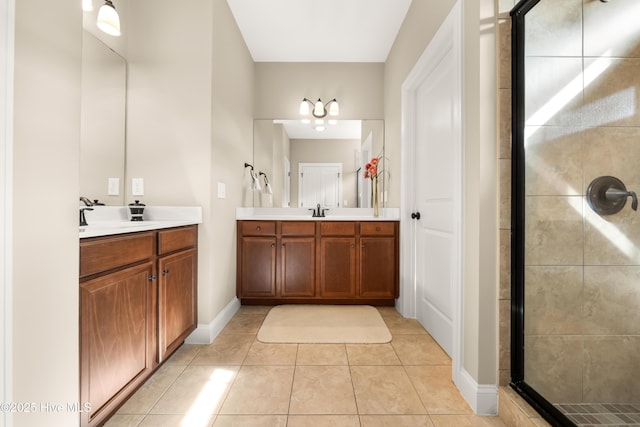 bathroom with two vanities, a sink, a shower stall, tile patterned flooring, and baseboards