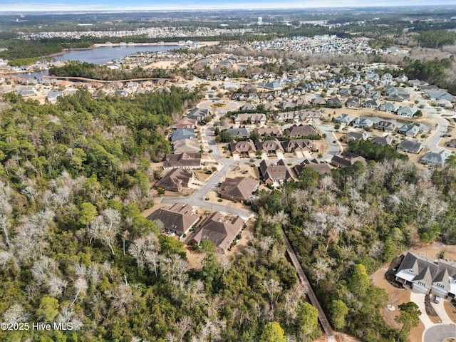 drone / aerial view featuring a water view, a wooded view, and a residential view