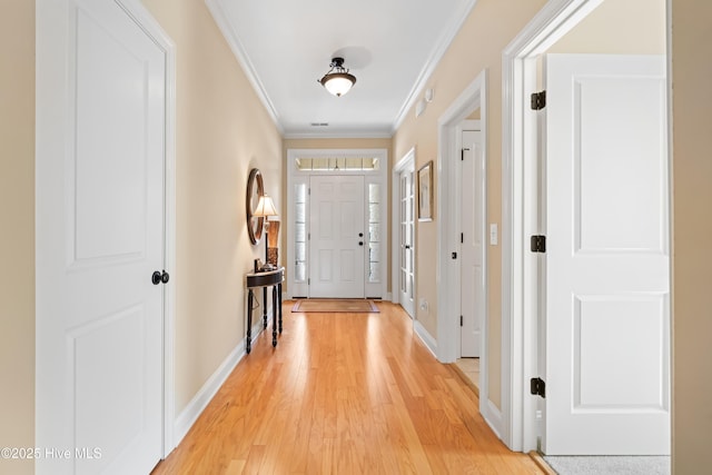 entryway featuring ornamental molding, light wood-style floors, and baseboards