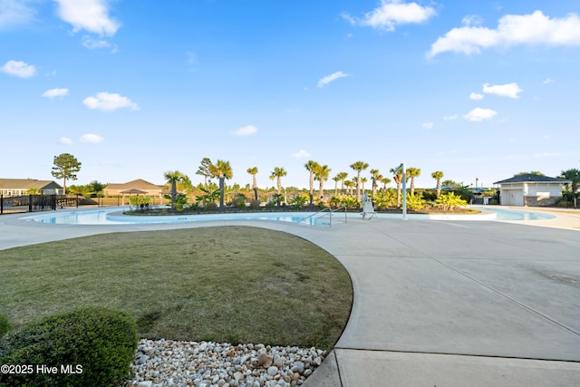 view of property's community featuring a yard, a swimming pool, and fence