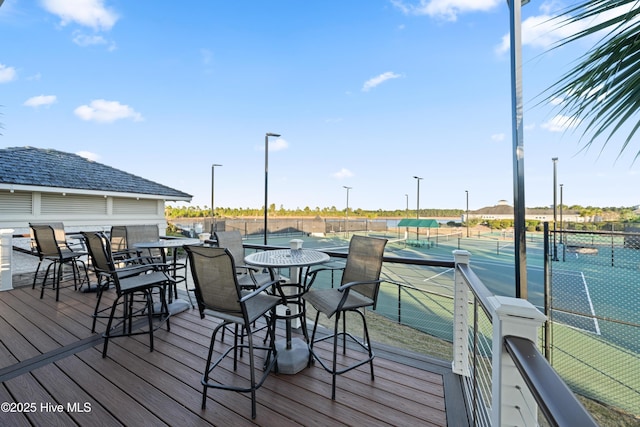 wooden terrace with a tennis court and fence