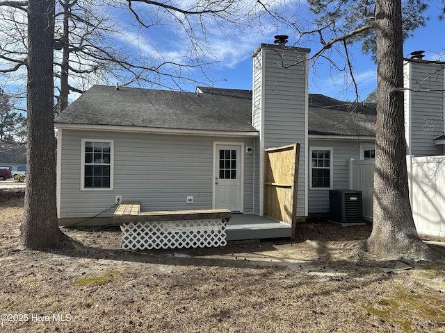 rear view of property featuring central AC unit, a chimney, a shingled roof, and a wooden deck