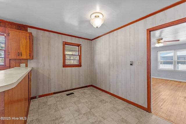 empty room featuring light floors, ornamental molding, visible vents, and baseboards