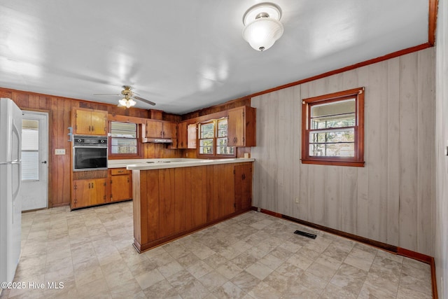 kitchen featuring brown cabinets, visible vents, light countertops, oven, and a peninsula