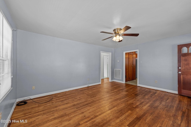 interior space with a ceiling fan, wood-type flooring, visible vents, and baseboards