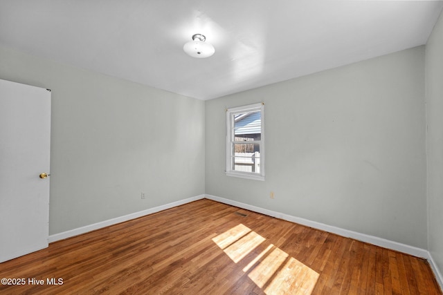 unfurnished room with baseboards and wood finished floors