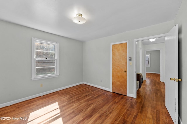 spare room featuring baseboards and wood finished floors