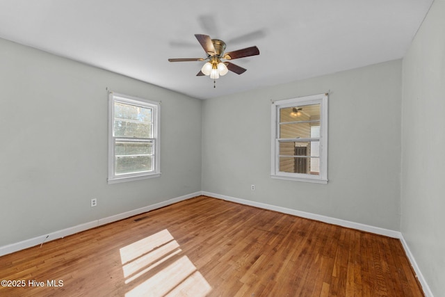 empty room featuring visible vents, ceiling fan, baseboards, and wood finished floors