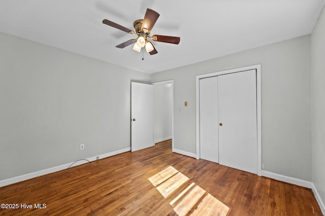 unfurnished bedroom with a closet, ceiling fan, baseboards, and wood finished floors