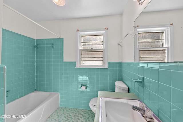 bathroom with tile walls, toilet, wainscoting, shower / tub combination, and tile patterned flooring