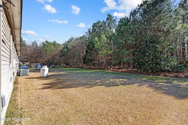 view of yard featuring cooling unit and a wooded view