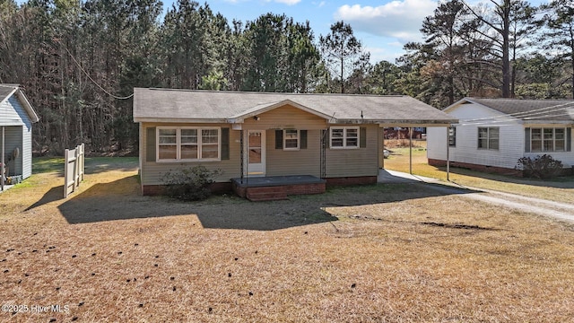 view of front of home featuring dirt driveway, an attached carport, crawl space, and a front yard