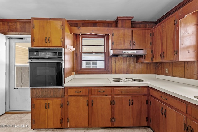 kitchen with under cabinet range hood, white electric stovetop, light countertops, and oven