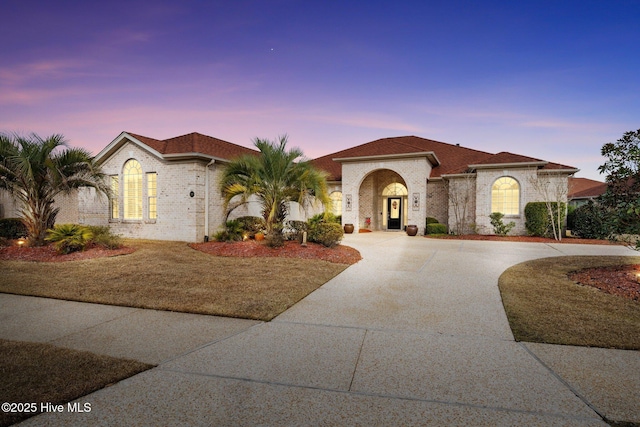 mediterranean / spanish-style house with concrete driveway and brick siding