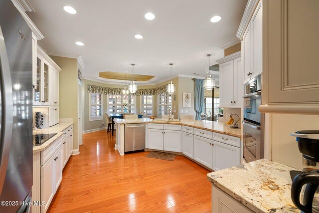 living room with ornamental molding, a fireplace, a tray ceiling, and wood finished floors