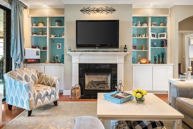 living area featuring ornamental molding, wood finished floors, and a tile fireplace