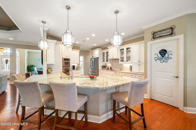 kitchen with appliances with stainless steel finishes, light wood-type flooring, a kitchen bar, and crown molding