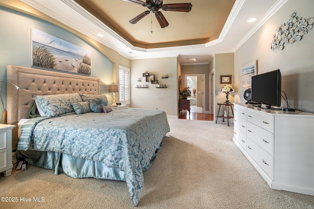 bedroom featuring light colored carpet, a tray ceiling, ornamental molding, recessed lighting, and a ceiling fan