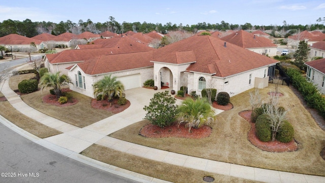 mediterranean / spanish-style house with concrete driveway, an attached garage, a residential view, and roof with shingles