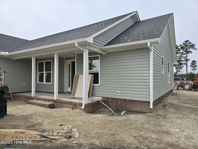 back of property featuring covered porch and roof with shingles