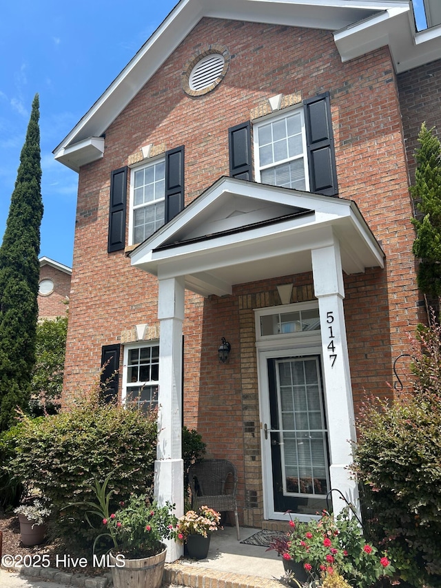 entrance to property with covered porch and brick siding