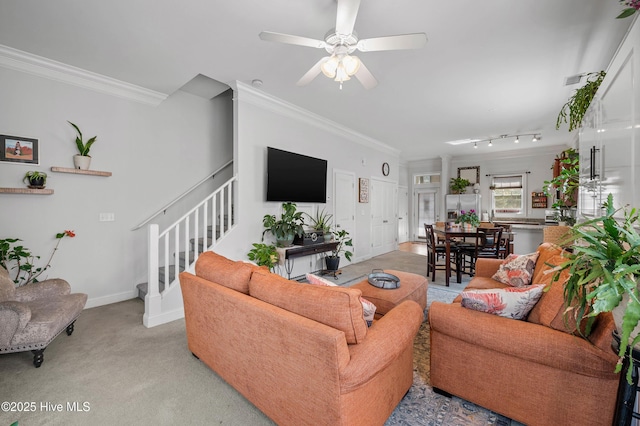 living room featuring baseboards, light colored carpet, ceiling fan, ornamental molding, and stairs