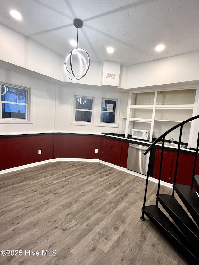 kitchen with recessed lighting, a wainscoted wall, wood finished floors, visible vents, and stainless steel dishwasher