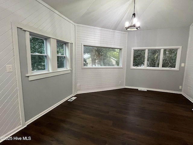 unfurnished room with plenty of natural light, wood finished floors, visible vents, and baseboards