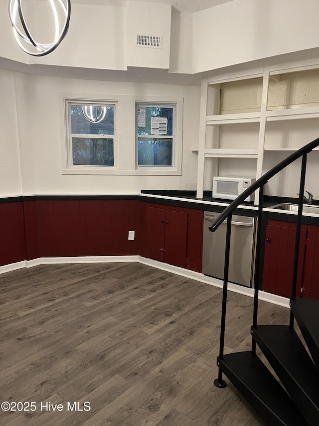 interior space featuring visible vents, dishwasher, white microwave, a wainscoted wall, and dark wood-type flooring