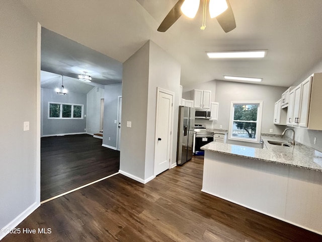 kitchen with a peninsula, vaulted ceiling, stainless steel appliances, and a sink