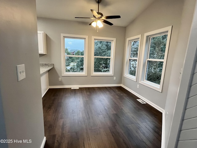 unfurnished dining area featuring dark wood-style floors, ceiling fan, visible vents, and baseboards