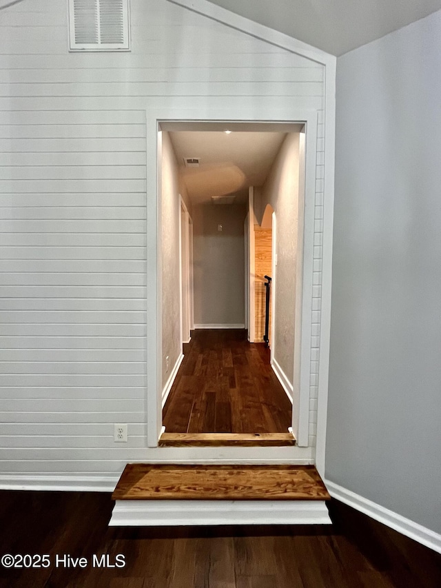 hall with wood finished floors, visible vents, and baseboards