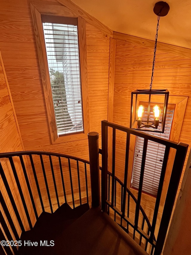 staircase featuring a chandelier and wooden walls