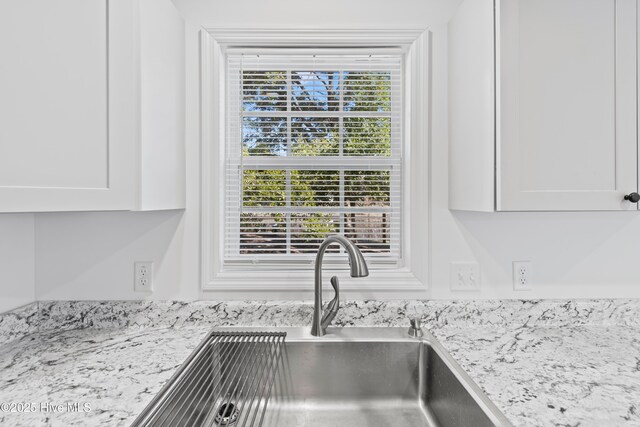 interior details featuring light stone countertops, white cabinets, and a sink