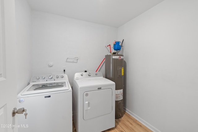 clothes washing area with light wood-style flooring, laundry area, baseboards, water heater, and washing machine and clothes dryer