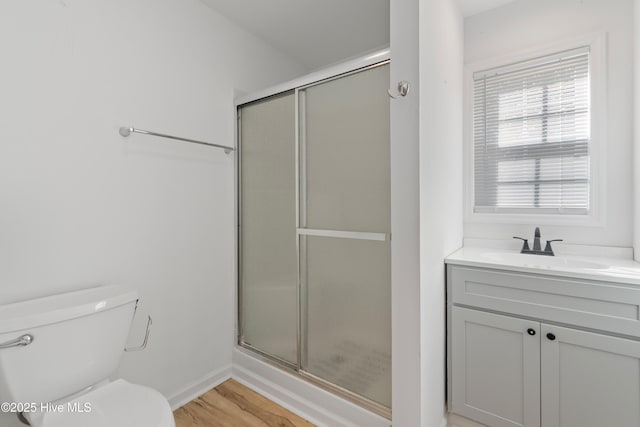 bathroom featuring a stall shower, vanity, toilet, and wood finished floors