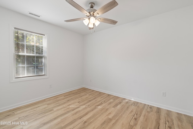 spare room featuring light wood-style floors, baseboards, visible vents, and a ceiling fan