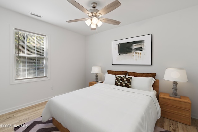 bedroom with ceiling fan, light wood finished floors, visible vents, and baseboards