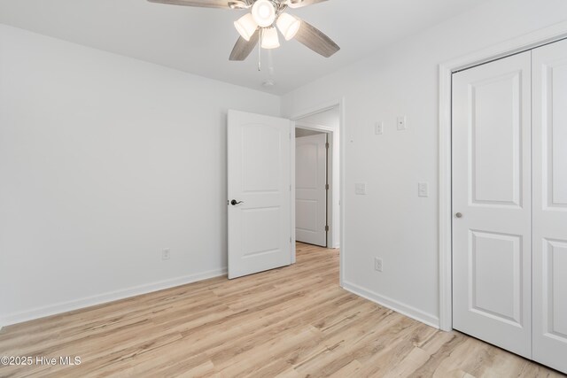 unfurnished bedroom featuring a closet, baseboards, ceiling fan, and light wood finished floors