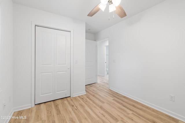 unfurnished bedroom featuring light wood-style floors, ceiling fan, baseboards, and a closet