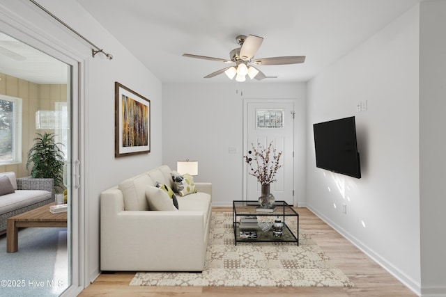 living area featuring light wood-type flooring, ceiling fan, and baseboards