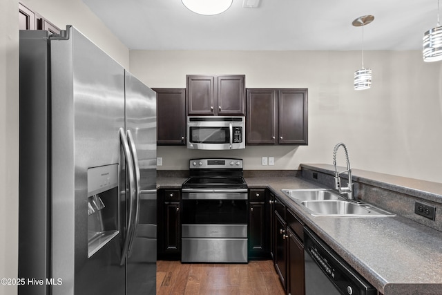 kitchen with dark wood-style flooring, dark countertops, appliances with stainless steel finishes, a sink, and dark brown cabinets