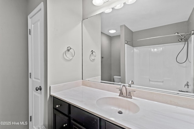 bathroom with walk in shower, vanity, and toilet